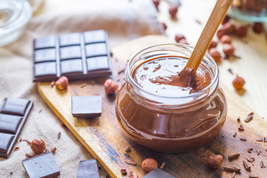 Sweet Dark Chocolate Sauce in a Bowl with Hazelnuts and Chocolate Pieces, Horizontal View