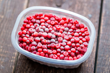 Frozen Cranberries in Container on Wooden Table, Horizontal View
