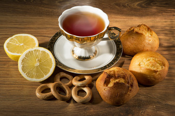 Cup of tea with a lemon and sweets. Still life against a dark background