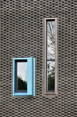 Modern patterned wall of black brick and with vertical colored windows.