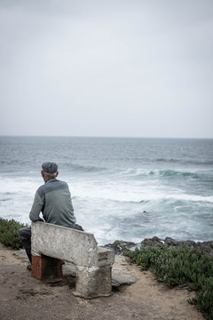 Man sits on bench and looks out to sea
