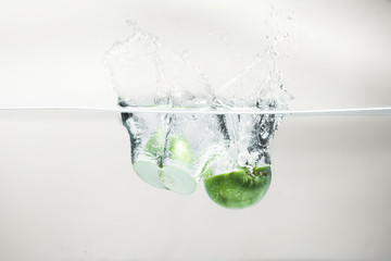 Green apple falling water on white background.