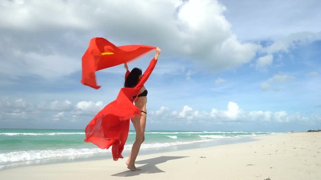 Young woman in red dress stand on the beach with vietnamese flag at her arms
