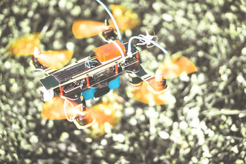Intellingent race drone hovering on a blurred grass of a park 