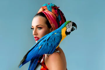 Gartenposter Portrait of young attractive woman in african style with ara parrot on her showlder on colorful background © k8most