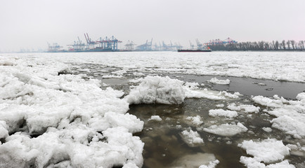Elbe river in winter. Ice pieces and winter shipping on the river and the port of Hamburg.