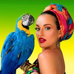 Portrait of young attractive woman in african style with ara parrot on her hand on colorful background © k8most