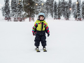 Child learn skiing in the mountains. Toddler kid in helmet learn