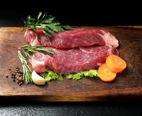 Raw marbled beef on a cutting board. On a black background