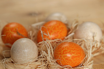 Easter. Orange and beige  eggs in the straw on wooden background