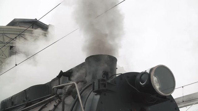 old black locomotive. steam smoking in real time.