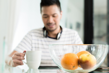 Indonesian man drinking coffee at breakfast