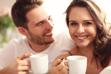 Young couple drinking coffee in bed