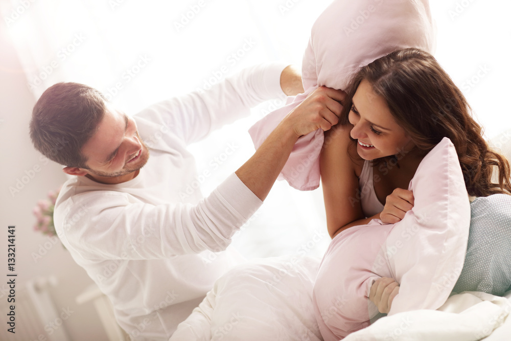 Wall mural happy couple having pillow fight