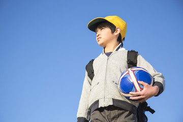 サッカーボールを持ち遠くを見る小学生の男の子