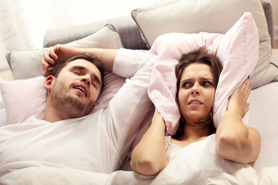 Angry woman in bed with snoring man