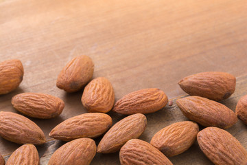 Roasted almonds on wooden background with space on the top.