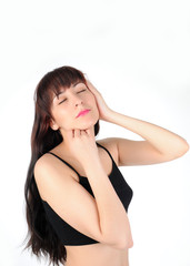 Fototapeta premium Young long-haired brunette woman in black lingerie on a white background with closed eyes touching face