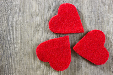 A three decorative red hearts on gray wooden background