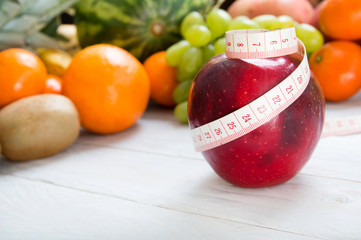 Apple and measuring tape over fruity background