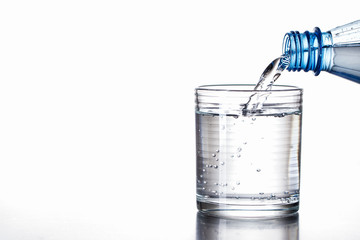 Mineralwasser aus Flasche in Glas eingeschenkt