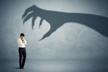 Fototapeta premium Business person afraid of a big monster claw shadow concept