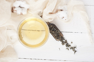 green tea and cotton on white wooden table