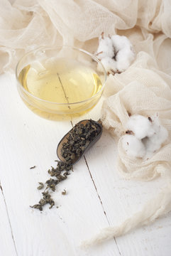green tea and cotton on white wooden table