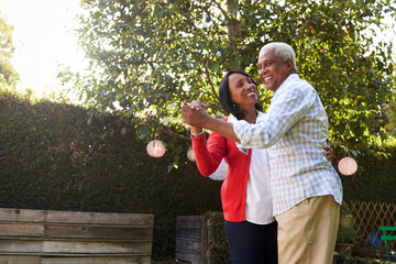 Senior black couple dancing in their back garden - Powered by Adobe