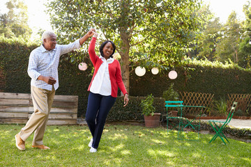 Senior black couple dance in their back garden, full length - Powered by Adobe