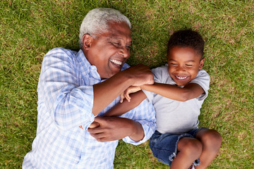 Fototapeta na wymiar Grandfather and grandson play lying on grass, aerial view