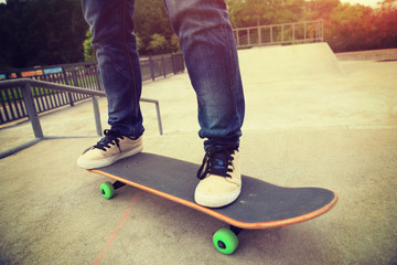 young skateboarder legs riding skateboard at skatepark