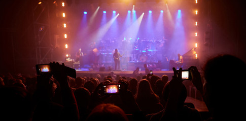 Viewers shoot a rock concert on mobile phones. View from the auditorium.