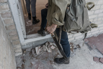 people go in an abandoned building. wandering boy. man in a protective cloak with a hood. Post apocalypse. traveling on foot in a post-apocalyptic world. teenagers with machetes