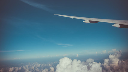 Airplane wing on a cloud blue sky scenery. (vintage style)