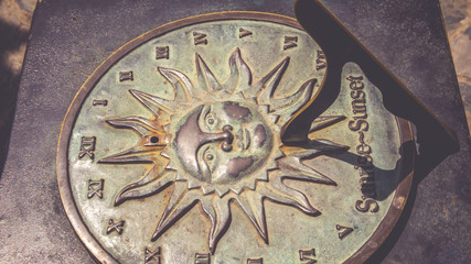 Old antique rusty floor sun clock and display sunset - sunrise on grunge metal texture background. (vintage style)