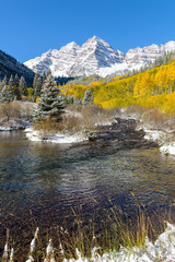 Maroon Bells and Creek - Vertical - An autumn morning after light overnight snow, Maroon Creek, filled with crystal-clear freshly melted water, flowing down from Maroon Bells. Aspen, Colorado, USA.