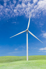 Fototapeta premium Wind turbines on grass field and blue sky