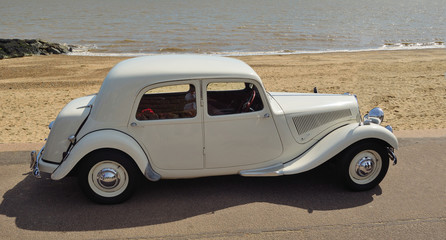  Classic White Motor car parked on seafront promenade.