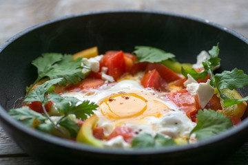 fried egg in a pan with tomatoes and greens