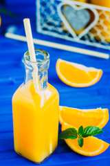 Fresh Orange juice in bottle on blue table background. Summer drink concept