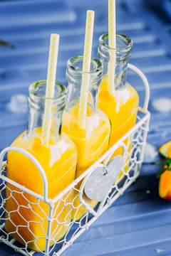 Fresh Orange juice in bottle on blue table background. Summer drink concept