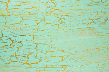 Cracked turquoise paint on the yellow surface