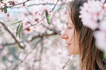 Young woman standing amongst blossoming almond tree