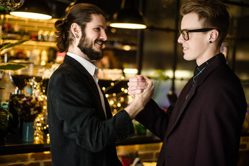 Two young businessman shaking hands and smiling. good deal