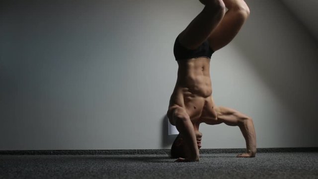 Athlete stands on his head and trains the body