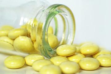 Yellow Medication Pills spilled out of Glass Drug Bottle taken closeup.
