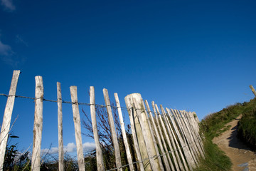 wooden fence posts along a coastal path with a deep blue sky