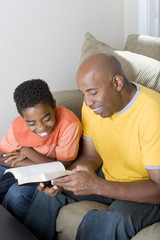 African American man reading with his son.