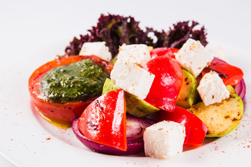 Salad with grilled vegetables on a white plate on a light background (close up)